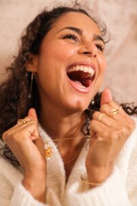 Cheerful young female with long curly hair in warm knitted sweater yelling happily and looking away
