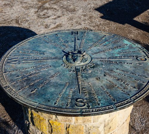 A detailed view of the compass rose direction indicator in Coesfeld, Germany, under bright daylight.